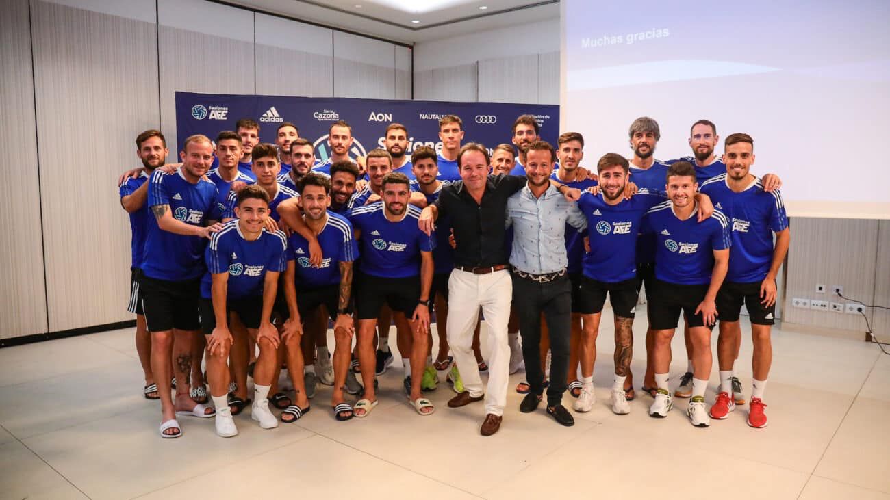 Deportistas posando con dos hombre de camisa